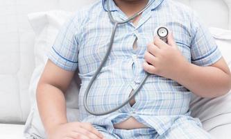 Obese fat boy check heart by stethoscope. photo
