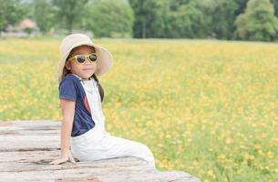 cute girl sit on wood and yellow flower background photo