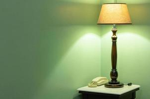 mesa lámpara con teléfono en cabecera en el dormitorio foto