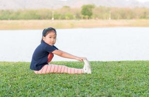 linda asiático niña ejercicio en verde césped foto