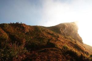 silueta turista en Valle de montaña con brumoso y niebla en invierno de amanecer brillante en el cielo a phu chee fah colina del Norte de Tailandia foto