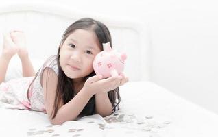 cute girl show piggybank on bed photo