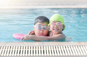 linda niña jugar nadar con hermano en nadando piscina foto