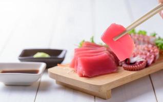 tuna sashimi on chopstick and on white wood background photo