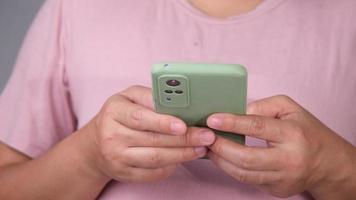 asiático hembra mano utilizando móvil teléfono a texto o charlar. cerca arriba de mujer utilizando inteligente teléfono video
