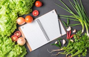 mix vegetables with blank notebook on black bcakground photo