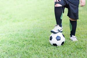 fútbol pelota con niño pies jugador en verde césped foto