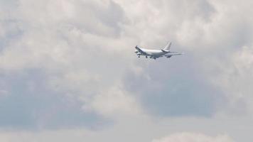 Four engine wide body aircraft flying in cloudy gray sky, long shot. Cargo airliner approaching for landing video