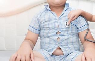 doctor check heart by stethoscope to obese asian boy photo