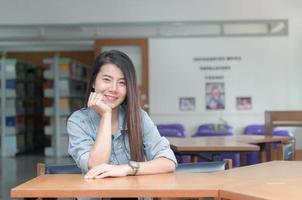confidente sonriente estudiante asiático niña en el biblioteca Universidad foto