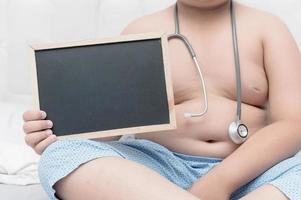 obese fat boy holding blank blackboard photo