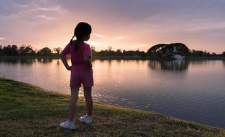 back side of little girl exercise on park with sunset photo