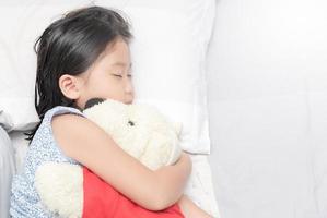 cute little asian girl sleep and hug doll photo