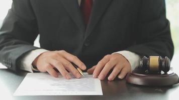 Business and lawyers discussing contract papers with brass scale on desk in office. Law, legal services, advice, justice and law concept picture with film grain effect video