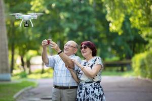 Happy elderly couple on a walk. Elderly husband and wife with a drone. Loving spouses in adulthood. photo