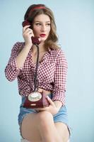 Woman in the style of the fifties. Beautiful retro woman with an old telephone. photo