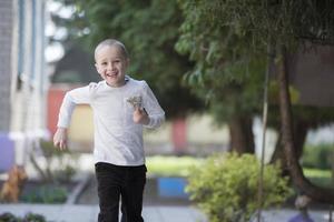 Happy seven year old boy playing on a summer street. photo