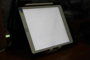 Photo of an empty tablet with white screen on the table