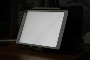 Photo of an empty tablet with white screen on the table