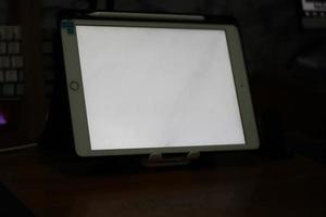 Photo of an empty tablet with white screen on the table