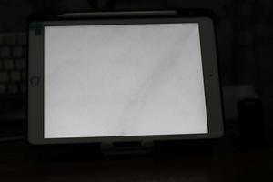 Photo of an empty tablet with white screen on the table