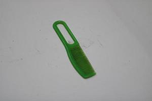 photo of a green hair comb made of plastic with a white background