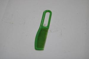 photo of a green hair comb made of plastic with a white background