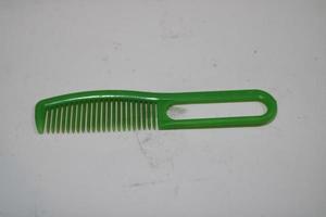 photo of a green hair comb made of plastic with a white background