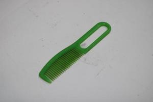 photo of a green hair comb made of plastic with a white background