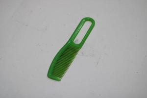 photo of a green hair comb made of plastic with a white background