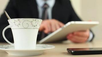Businessman take a break for tea time, using tablet, selective focus video