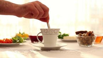 un' tazza di tè è servito nel prima colazione volta, verdure e prima colazione Alimenti su tavolo, selettivo messa a fuoco video