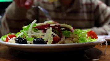 Eating a salad with friends in restaurant, eating a salad with a squeeze of lemon, selective focus video