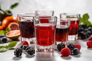 Different glasses with forest berries juice with berries and fruits around. . photo