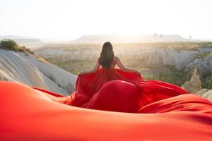 un niña en un volador vestir con un largo tren en el antecedentes de globos en capadocia. foto