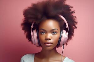 Dark-skinned African girl with black curly hair, wearing pink headphones on a pink background. Studio portrait. photo