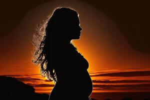 Silhouette of a pregnant woman against the background of the sunset. photo