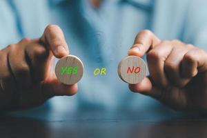 Concept of choice yes or no on wooden cubic blocks. Think with Yes or No choice, Business choices for difficult situations, Business woman hands holding two wooden with yes or no word on it. photo