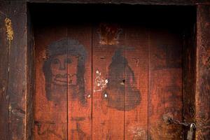 There are simple blessing graffiti on the red wooden door of the stone house photo