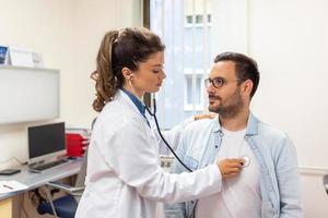 Caring Caucasian female doctor use phonendoscope examine male patient heart rate at consultation in hospital. Woman nurse or GP use stethoscope listen to man heartbeat in clinic. photo