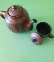 Clay teapot and cup on green background. photo