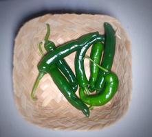 Ripe green chilies in a bamboo basket on a grey background. photo