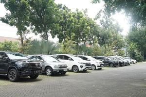 solo, Indonesia - febrero 20, 2023 coche estacionamiento en grande asfalto estacionamiento lote con árboles, blanco nube y azul cielo antecedentes foto