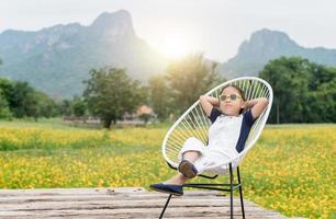 linda niña sentar y relajarse en silla y amarillo flor antecedentes foto