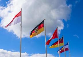 Several flags of German federal states waving in the wind against a sunny sky photo