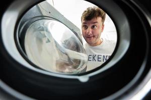 Man view from washing machine inside. Male does laundry daily routine. photo