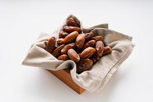 Dried dates fruit in wooden tray with soft napkin isolated on white background. photo
