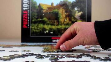 Person reveal the correct table by looking at the main picture, person putting together the correct puzzle pieces by looking at the main picture, selective focus video