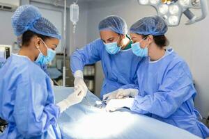 Surgeons operating below lighting equipment. Male and female doctors are wearing blue scrubs. They are working in hospital. photo