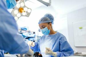 Medical team performing operation. Group of surgeon at work in operating theatre toned in blue. Doctor operation in operation room at hospital concept for insurance advertising. photo